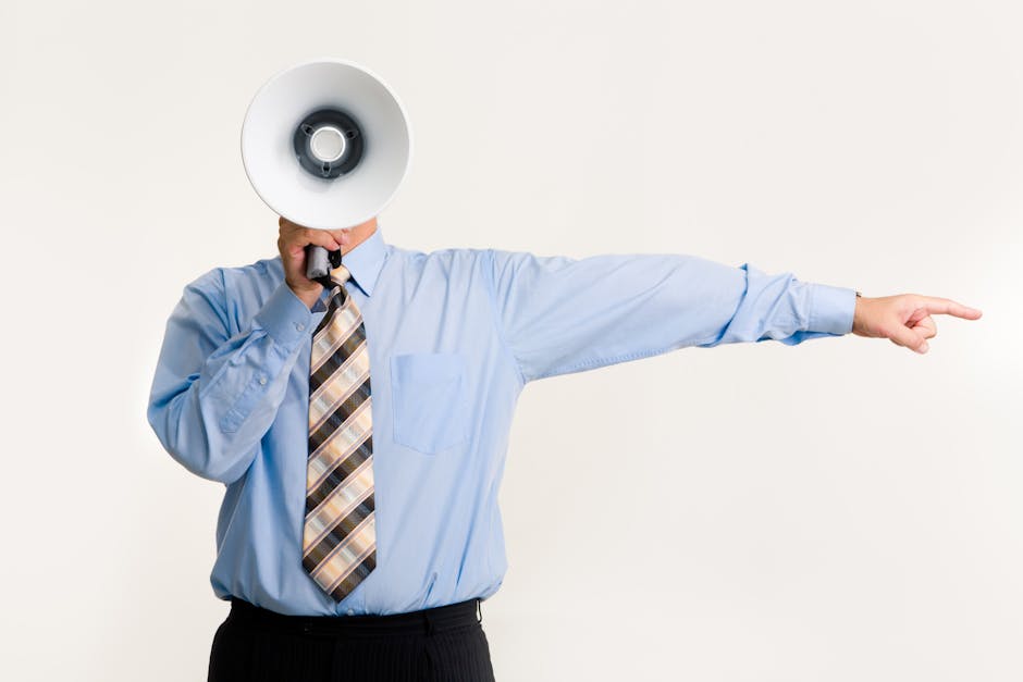 Businessman in blue shirt using a megaphone while pointing, isolated on white background