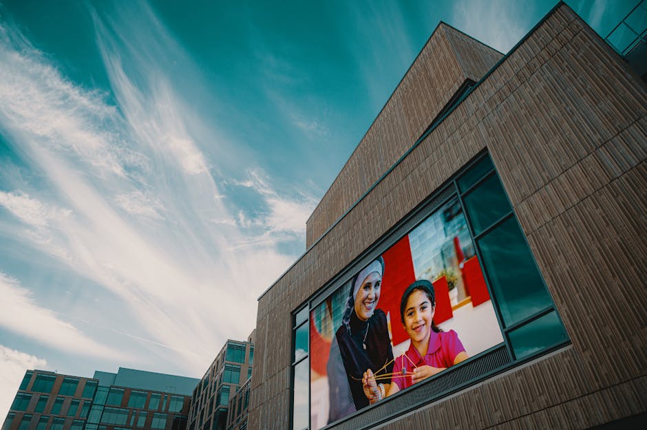Modern building facade showcasing a large digital screen displaying a vibrant image against a blue sky